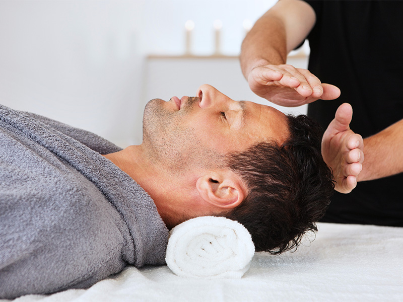 man having reiki performed on him