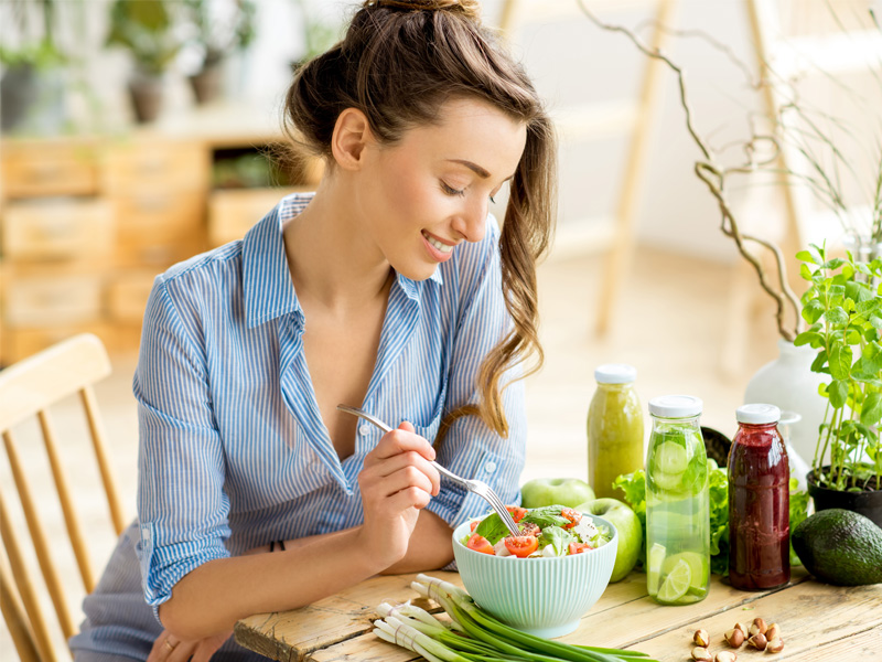 Woman at table eating salad and healthy drinks