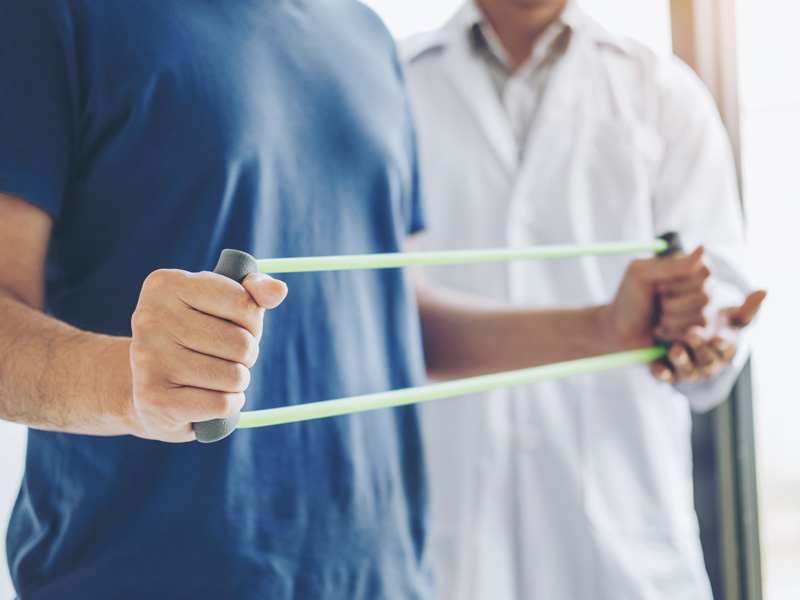 Man using rubber band tool to help with strength 